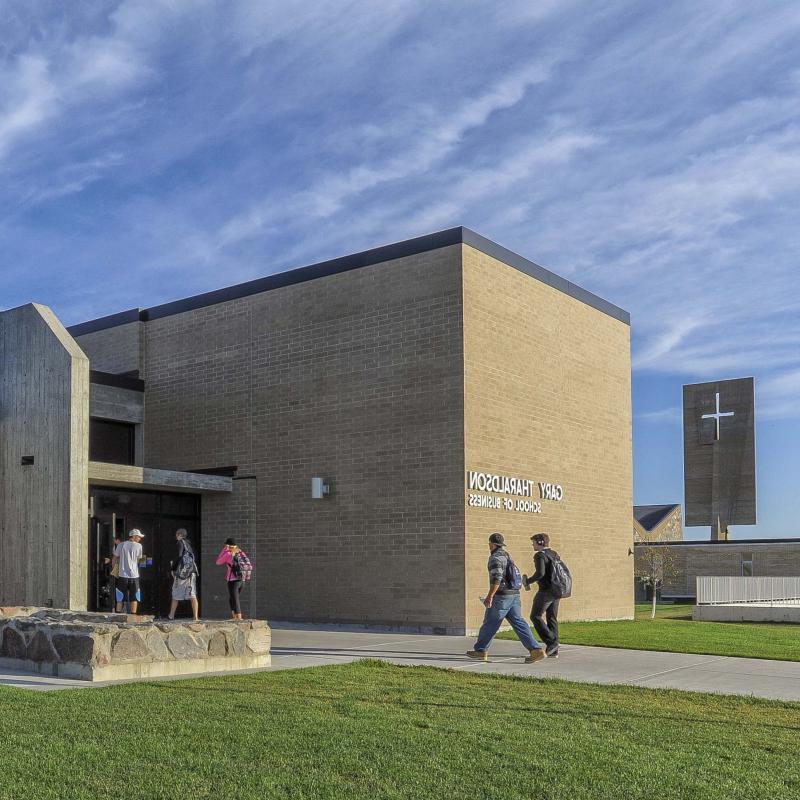 Five students walking into the Gary Tharaldson School of Business